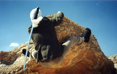 an Israeli Ninjutsu practitioner climbing a wall with a sword in his scarf